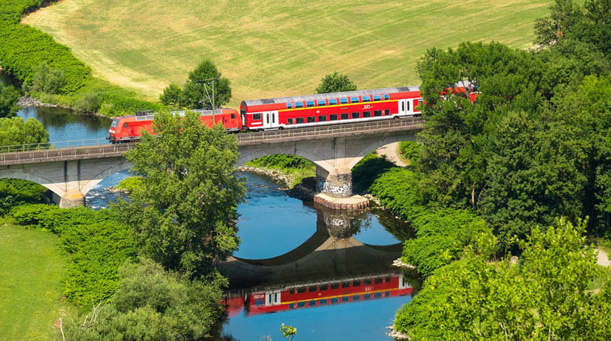 Европейский поезд едет через реку и красивые луга